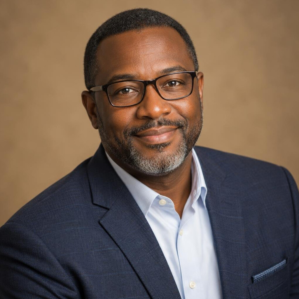 Studio portrait of a Black man with glasses in a blazer